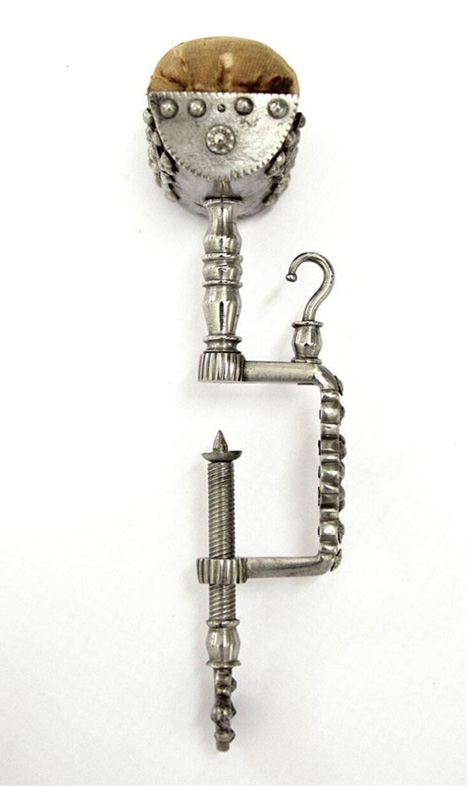 pin cushion above a decorative, silver metal screw-clamp