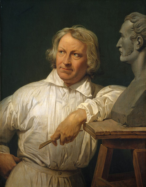 Bertel Thorvaldsen looking left, leaning with his left elbow on a stool with a bust of a man's head