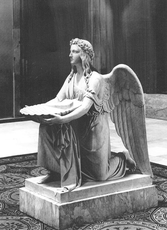 angel on one knee holding a shell-shaped basin; carpet has circular design with floral patterns