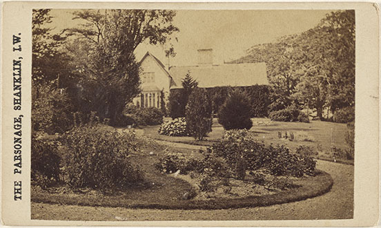 House with annex behind a myrtle tree and sweeping path through flower beds