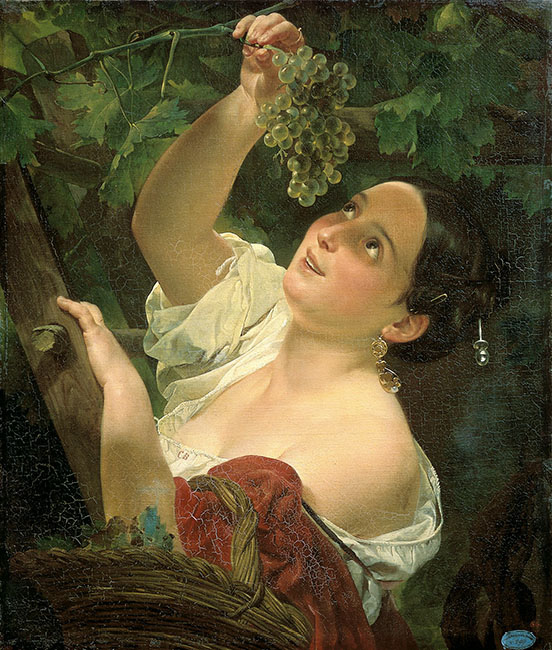 Smiling woman looking up to the left, pulling a bunch of green grapes on a branch down towards her face